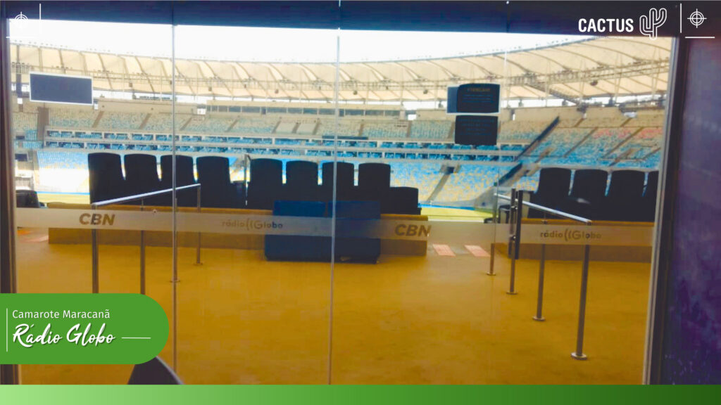 Vista de dentro do camarote da radio globo, através de portas de vidro, para a parte interna do estádio Maracanã mostrando as arquibancadas e o gramado